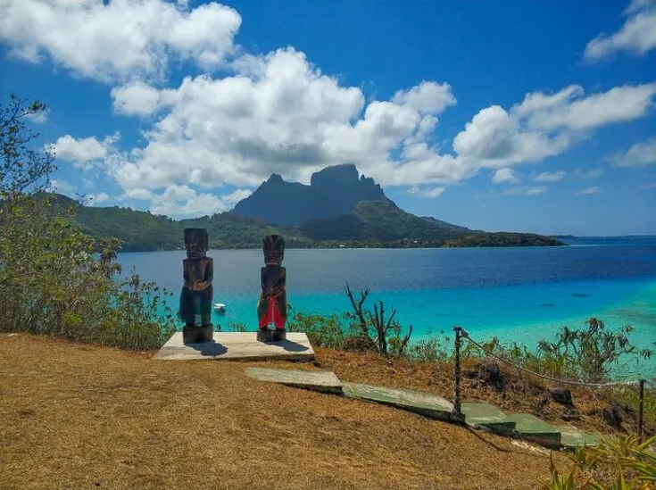 Two Tiki statues overlooking the lagoon and Mata Pupu and Mt Otemanu bora bora